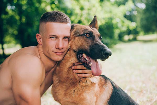 Junger Mann umarmt Schäferhund.